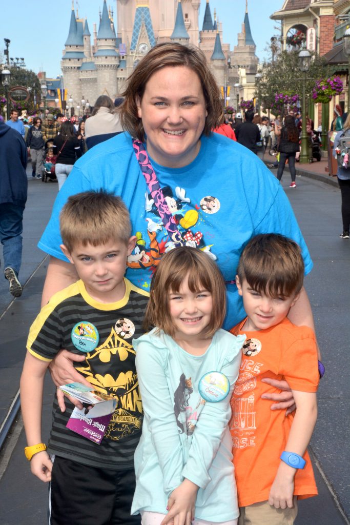 Mom and three children standing in front of the Disney castle